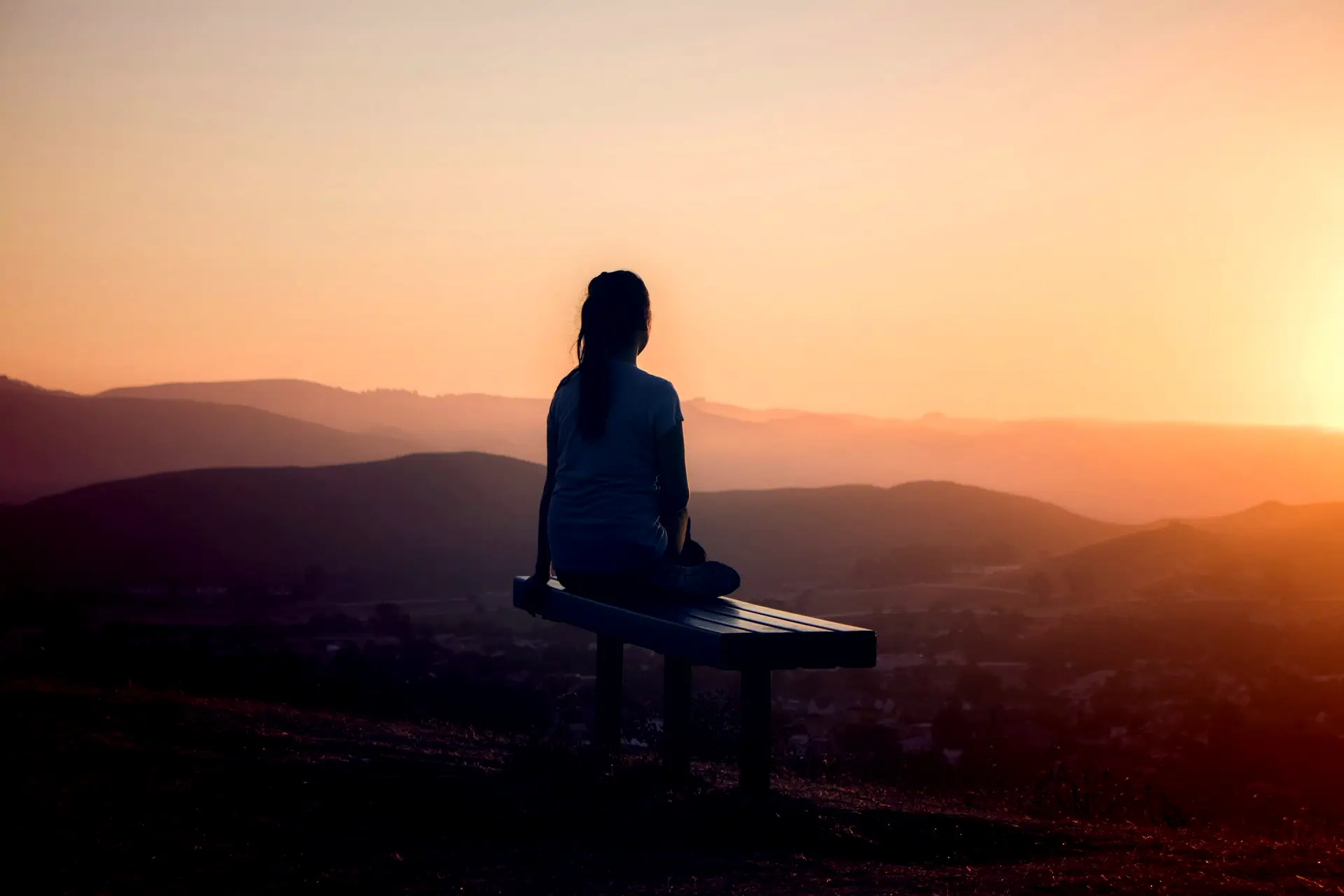 woman sitting on bench over viewing mountain
